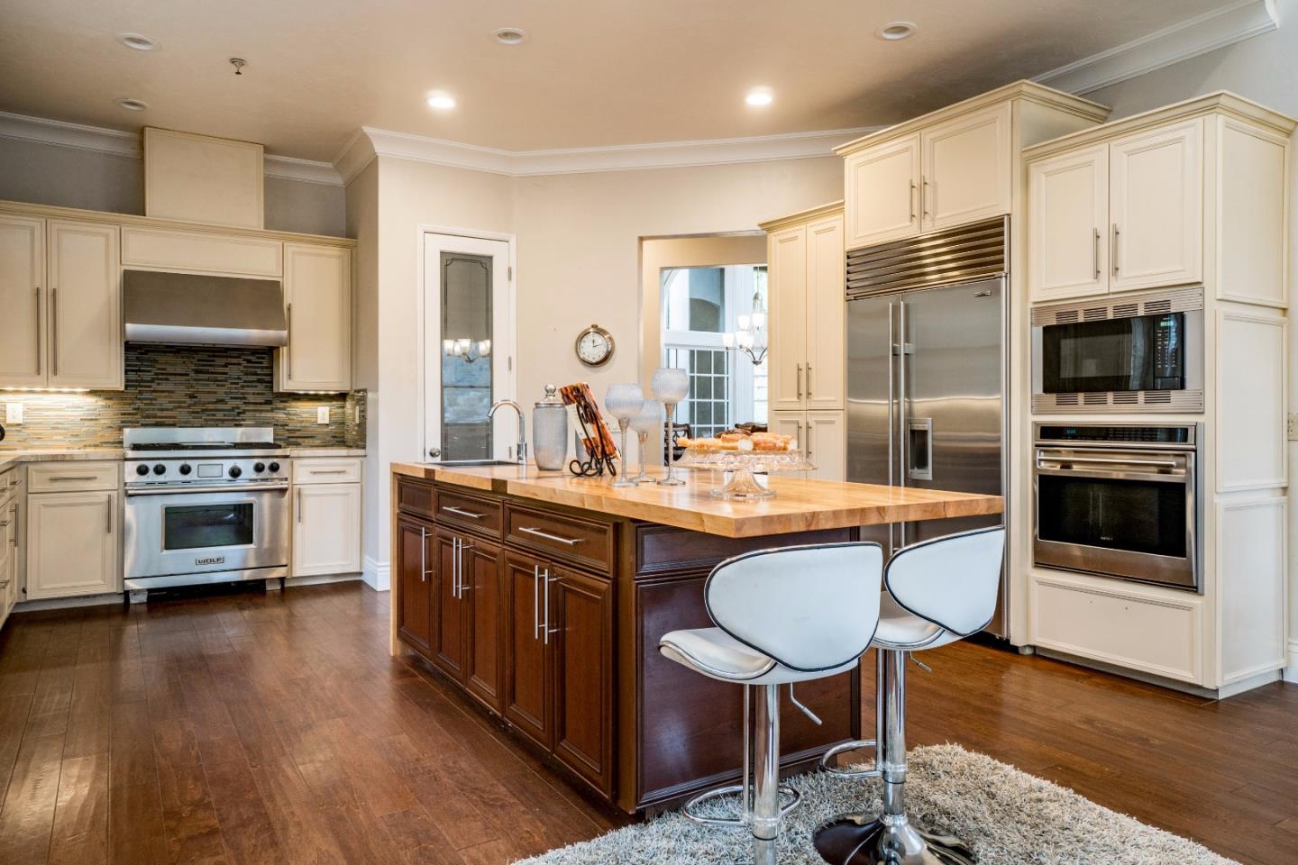 9945 Eddy Road Carmel, CA 93923 - Photo 9 of 31 a kitchen with stainless steel appliances granite countertop a stove a sink a microwave a refrigerator and white cabinets with wooden floor