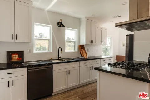 a view of a hallway with wooden floor and a bathroom