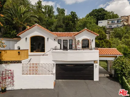 a view of a white house with a yard and potted plants