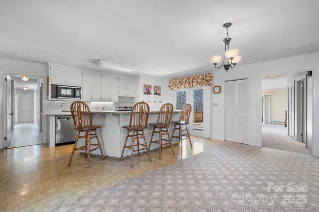a view of a dining room and livingroom with furniture wooden floor a chandelier