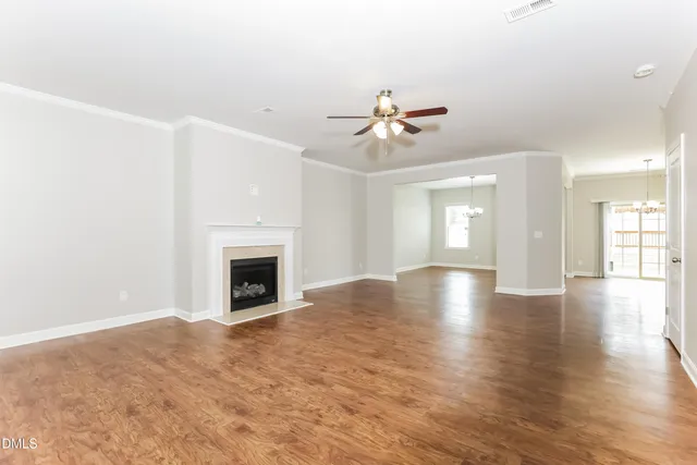 a view of a livingroom with a fireplace a ceiling fan and windows