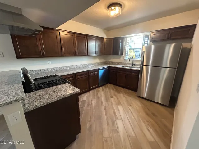a kitchen with granite countertop a refrigerator and a stove top oven