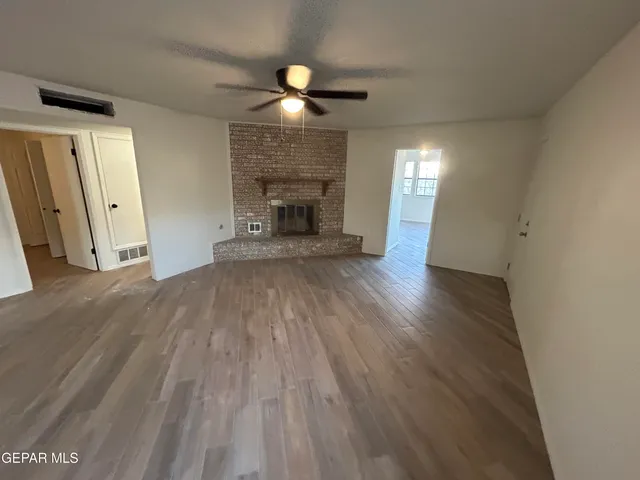 an empty room with wooden floor fireplace and windows