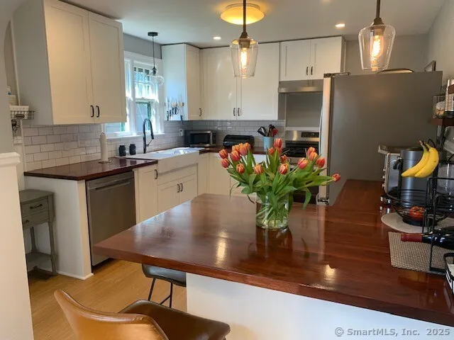 a kitchen with stainless steel appliances granite countertop sink stove refrigerator dining table and chairs