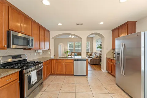 a large kitchen with stainless steel appliances granite countertop a stove a sink dishwasher a refrigerator and a microwave oven on the granite countertops