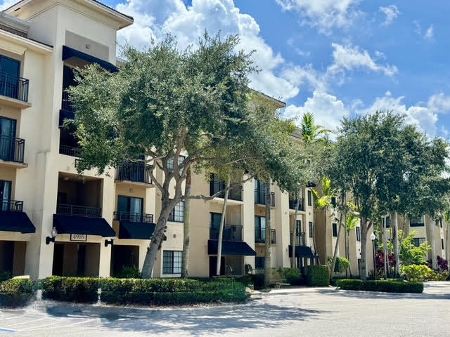 4905 Midtown Lane, Unit 2405 Palm Beach Gardens, FL 33418 - Photo 2 of 28 a front view of a multi story residential apartment building with yard and parking space