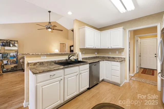 a kitchen with granite countertop a sink stainless steel appliances and cabinets