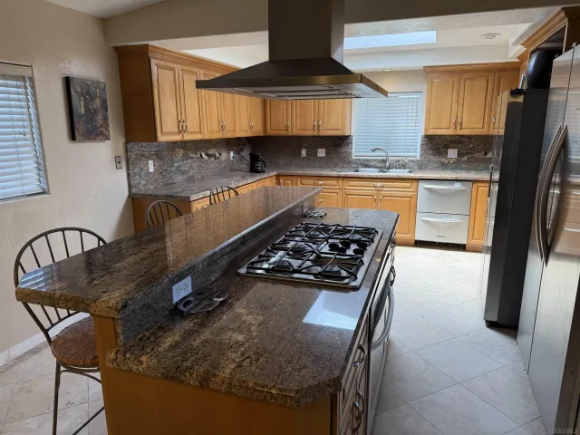 a kitchen with granite countertop a stove a sink and a refrigerator
