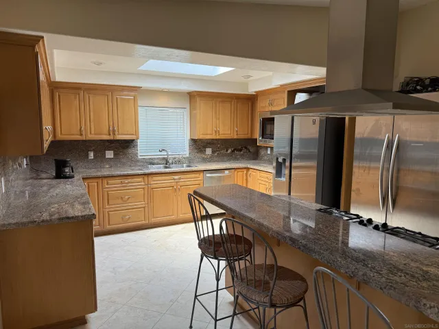 a kitchen with stainless steel appliances granite countertop a sink a stove a microwave a refrigerator and cabinets