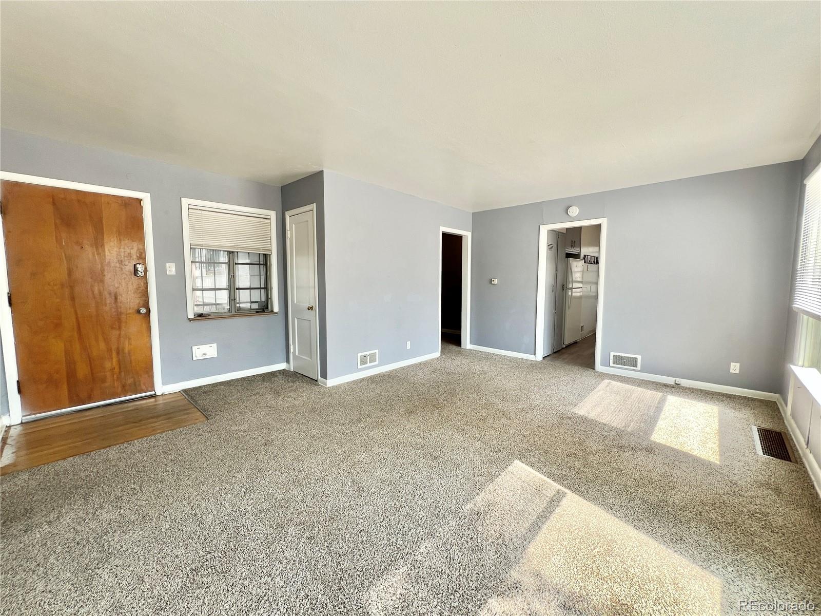 3580 Oneida Street Denver, CO 80207 - Photo 6 of 13 a view of an empty room with window and a kitchen