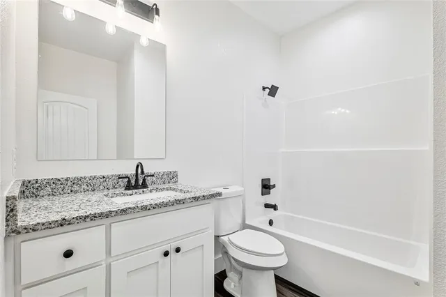 a bathroom with a granite countertop sink a toilet and bathtub
