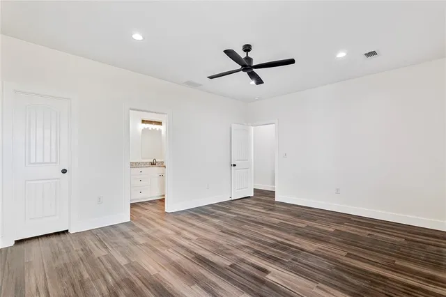 a view of empty room with wooden floor and ceiling fan