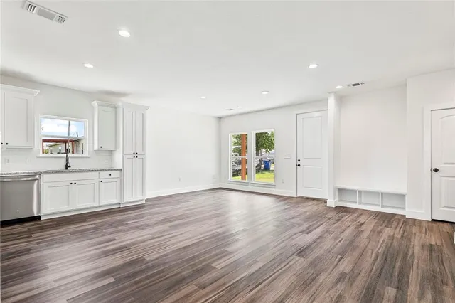 a view of an empty room with a window and wooden floor