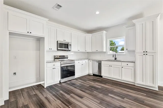 a kitchen with granite countertop white cabinets and stainless steel appliances