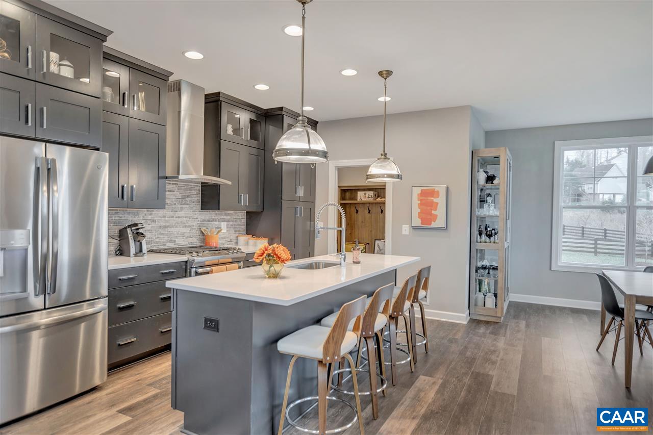 3490 Thicket Run Place Charlottesville, VA 22911 - Photo 9 of 36 a kitchen with stainless steel appliances a dining table chairs refrigerator and sink