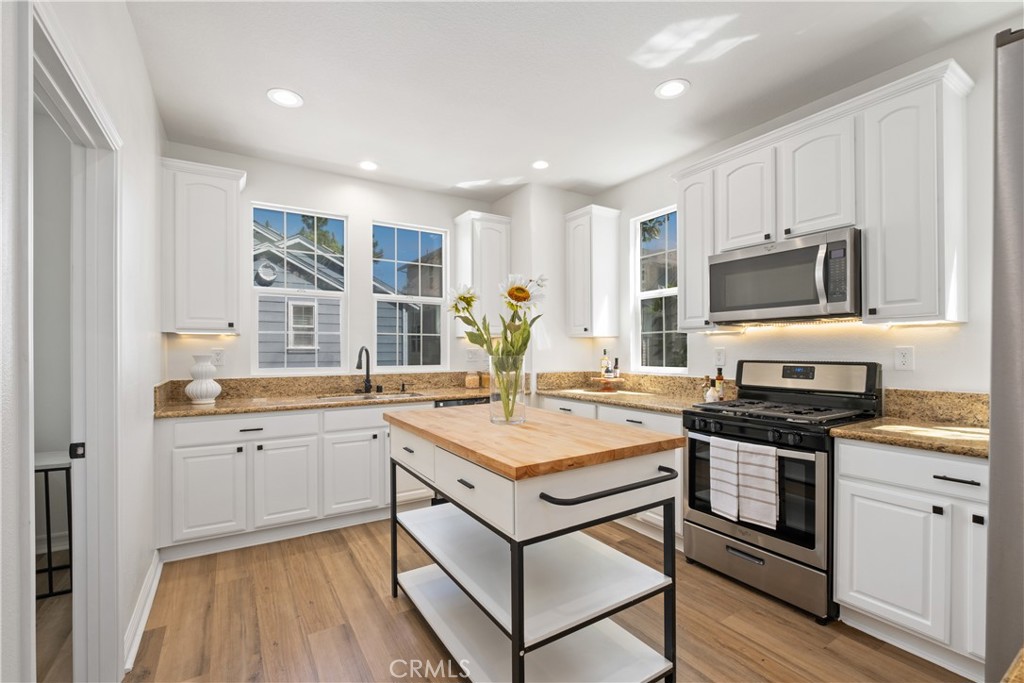 27 Reese Creek Ladera Ranch, CA 92694 - Photo 19 of 40 a kitchen with stainless steel appliances granite countertop a stove top oven a sink dishwasher and a refrigerator with wooden floor