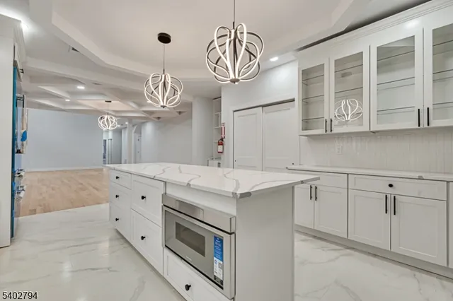a kitchen with cabinets stainless steel appliances and chandelier