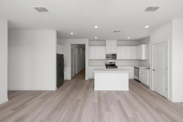 a kitchen with a refrigerator and white cabinets