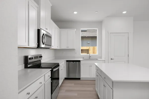 a kitchen with stainless steel appliances granite countertop a sink and dishwasher a stove top oven with white cabinets