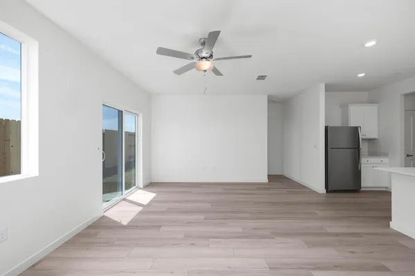 a view of an empty room with wooden floor and a ceiling fan