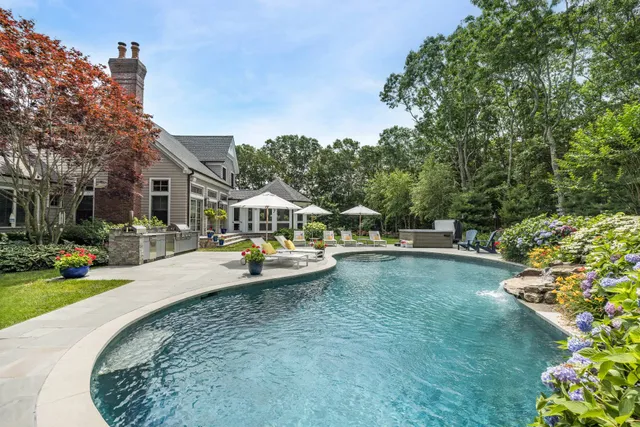 a view of a swimming pool with lawn chairs and plants