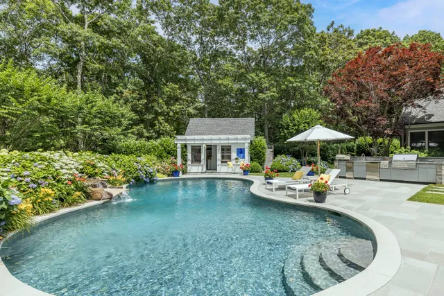 a view of a swimming pool with a lounge chair and a small yard