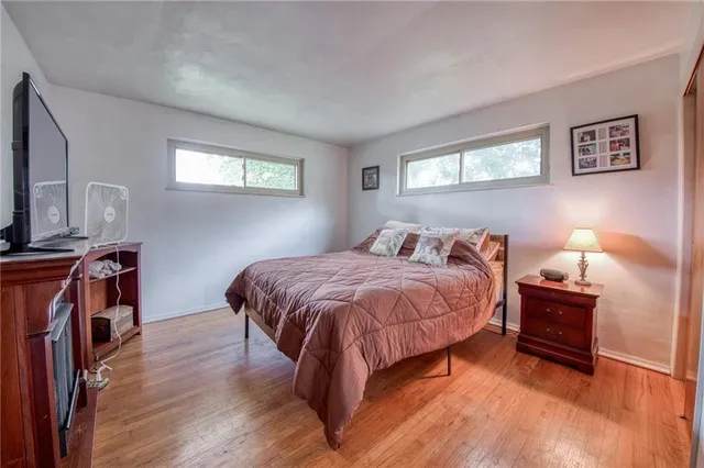 a spacious bedroom with a bed and a flat tv screen on dresser