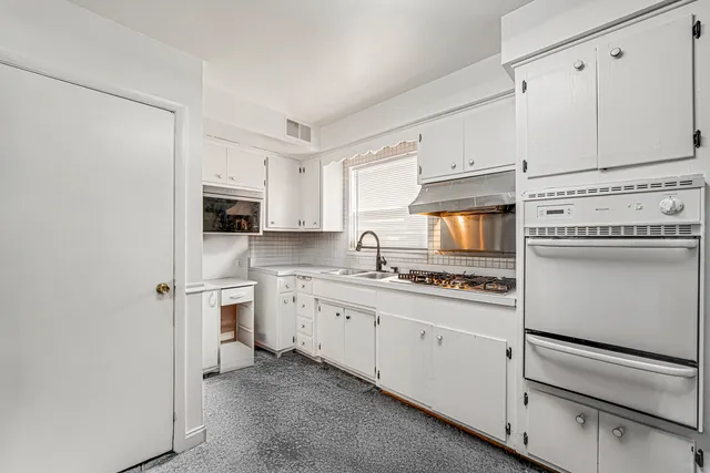 a kitchen with granite countertop white cabinets and white appliances
