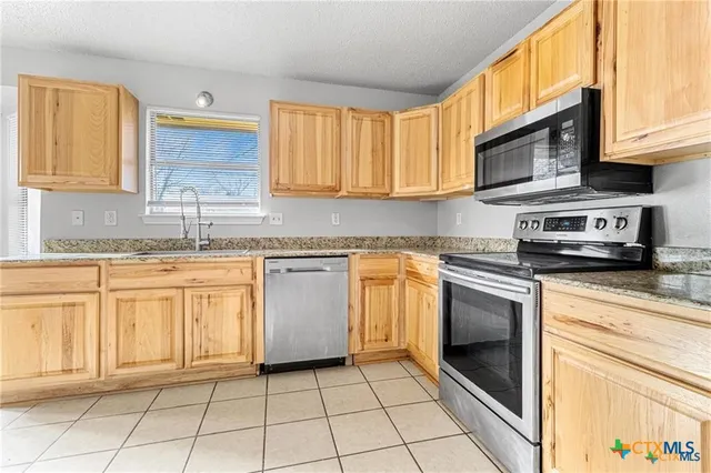 a kitchen with stainless steel appliances granite countertop a stove sink and cabinets
