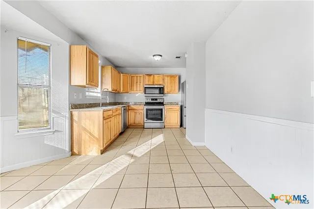 a large kitchen with a stove a sink dishwasher and a refrigerator