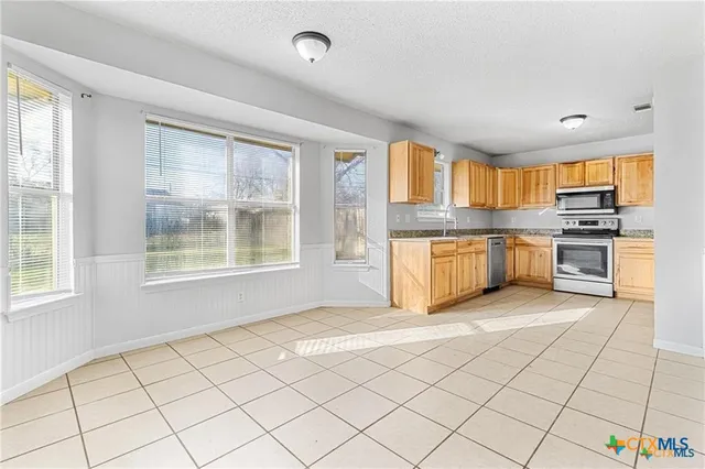 a large kitchen with stainless steel appliances granite countertop a stove a sink and a microwave