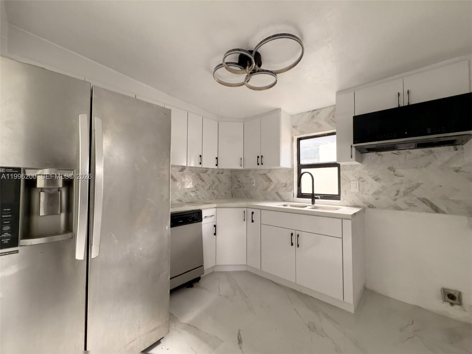 1261 Northwest 45th Street Miami, FL 33142 - Photo 48 of 95 a kitchen with granite countertop cabinets a sink stainless steel appliances and a counter space