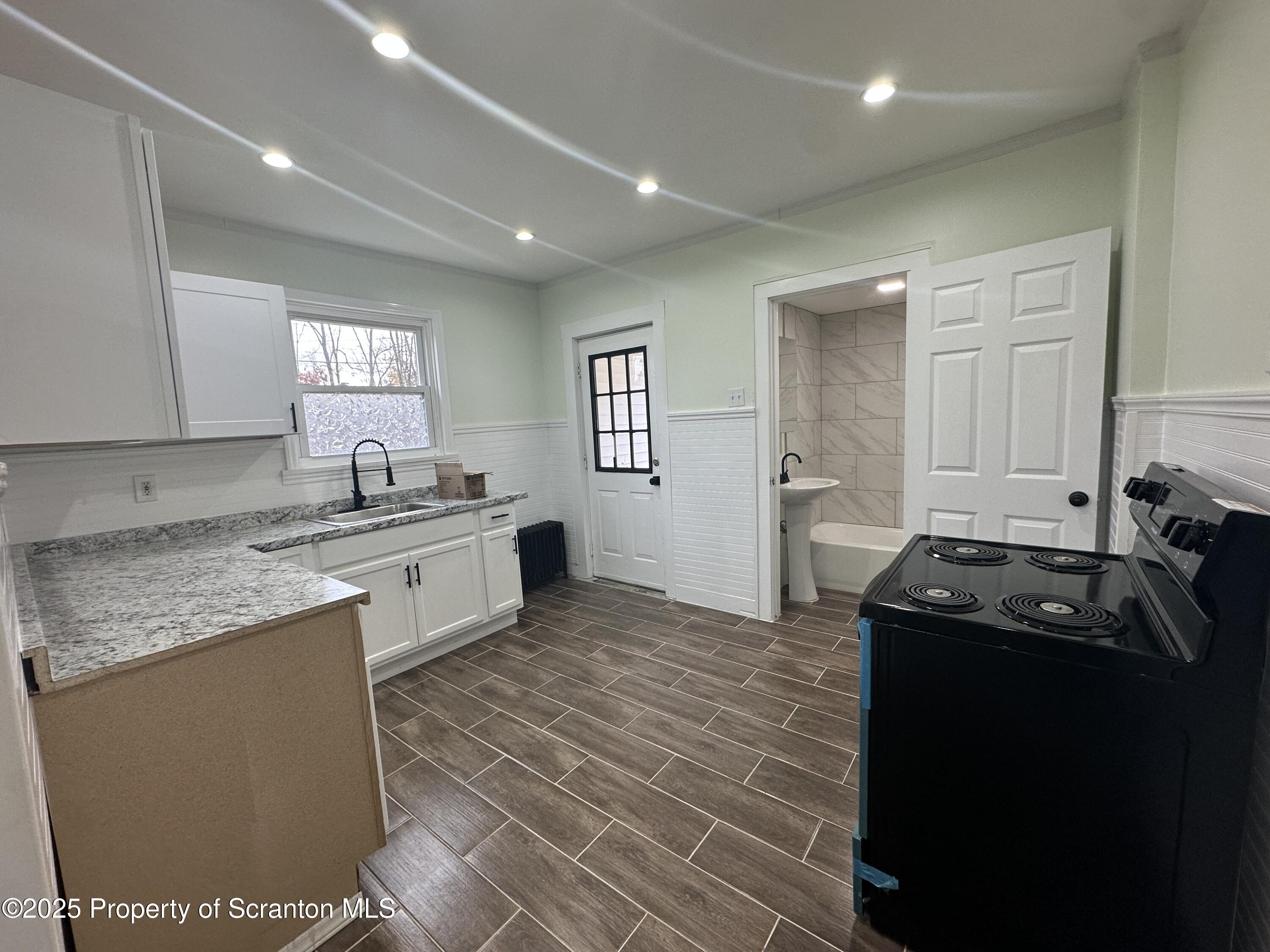 a kitchen with granite countertop a sink stove and cabinets