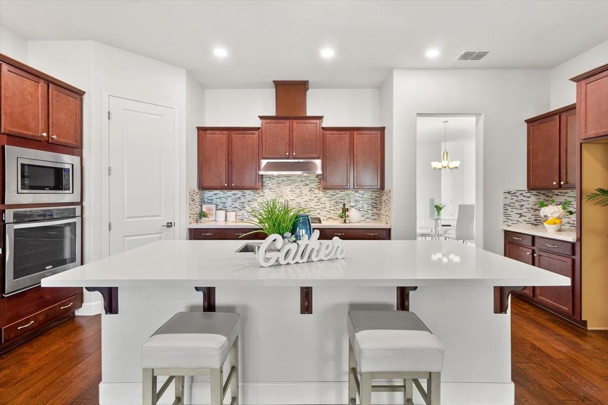 7842 Cinnamon Way Gilroy, CA 95020 - Photo 24 of 51 a kitchen with kitchen island granite countertop a table and chairs