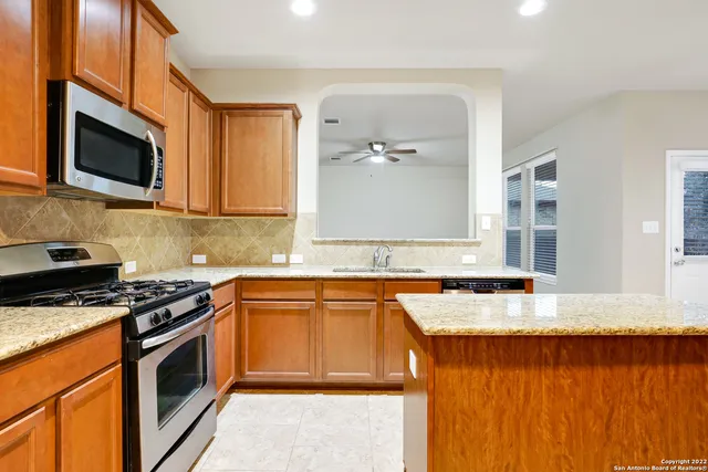 a kitchen with stainless steel appliances granite countertop a stove a microwave and wooden cabinets