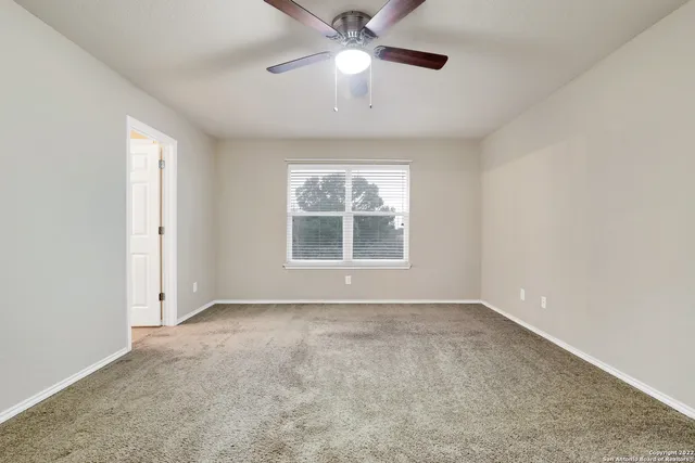 an empty room with a window and a ceiling fan