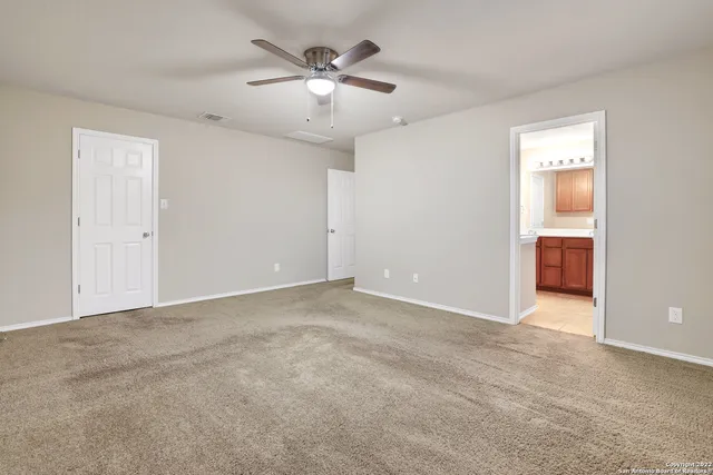 an empty room with chandelier fan and windows