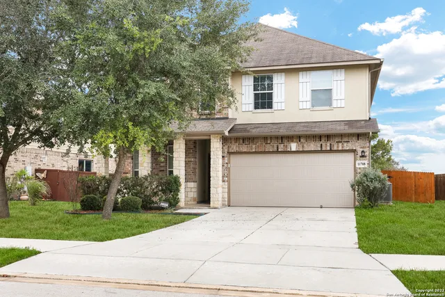 front view of house with a yard and trees