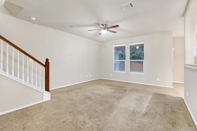 an empty room with windows and fan