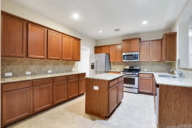 a kitchen with stainless steel appliances granite countertop wooden cabinets a stove top oven a sink and dishwasher