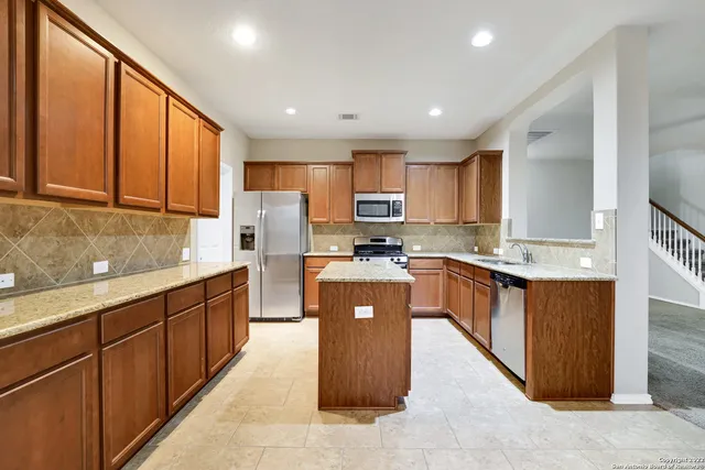a large kitchen with stainless steel appliances kitchen island granite countertop wooden cabinets a sink and a stove