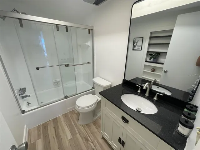 a bathroom with a granite countertop sink toilet a mirror and shower