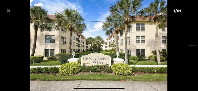 a front view of a multi story residential apartment building with a yard and large trees