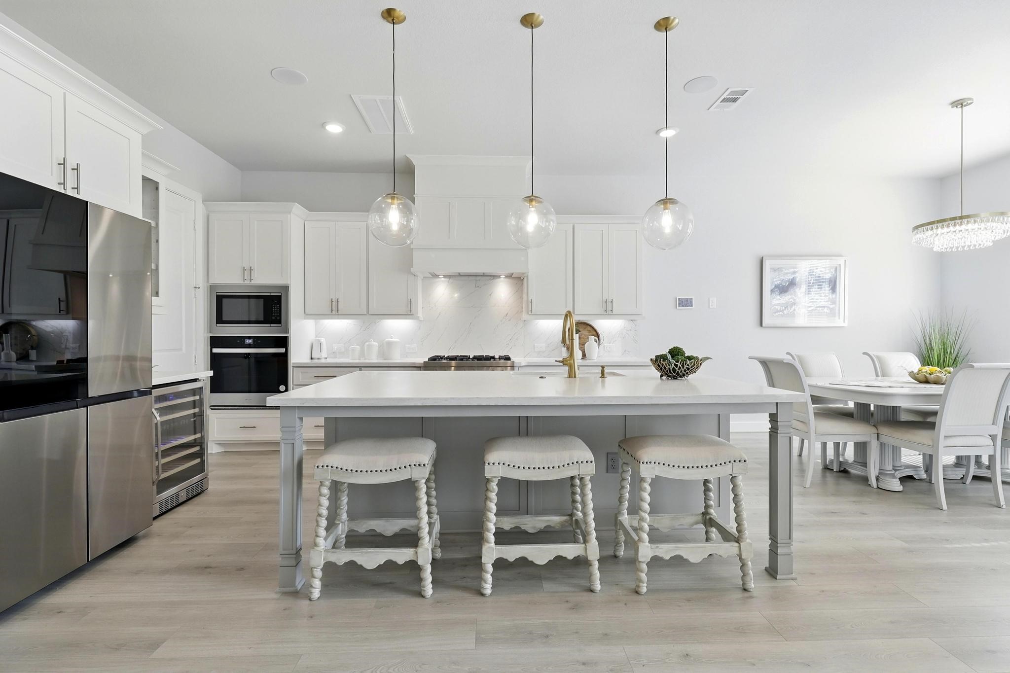 26923 Arethusa Court Spring, TX 77389 - Photo 8 of 44 This kitchen features a sleek and modern design with white cabinetry, stainless steel appliances, and a spacious quartz island ideal for seating. Pendant lighting adds elegance,
