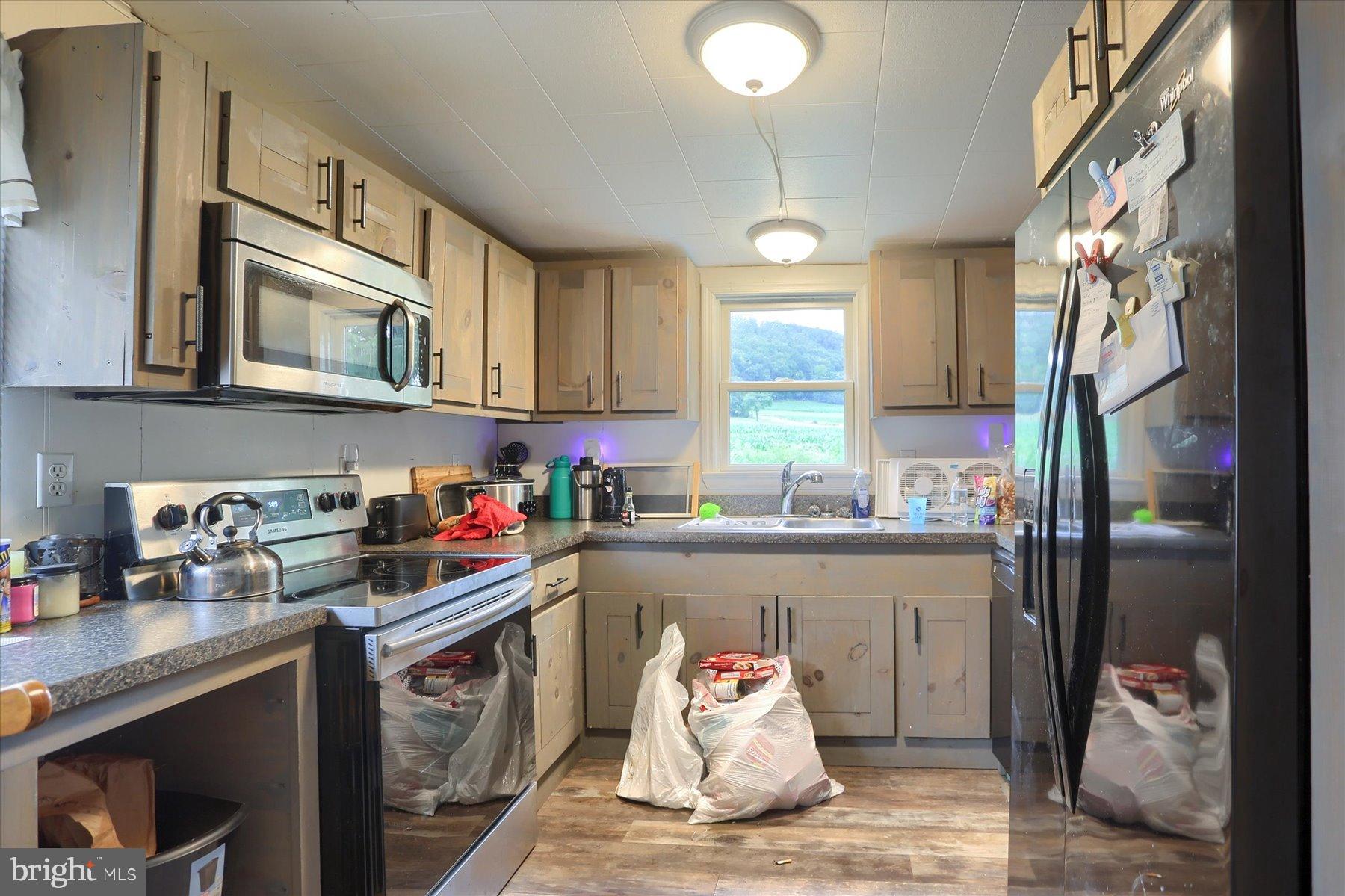 207 Mill Race Road Millerstown, PA 17062 - Photo 8 of 34 a kitchen with stainless steel appliances granite countertop a refrigerator a sink dishwasher a stove and white countertops with wooden floor
