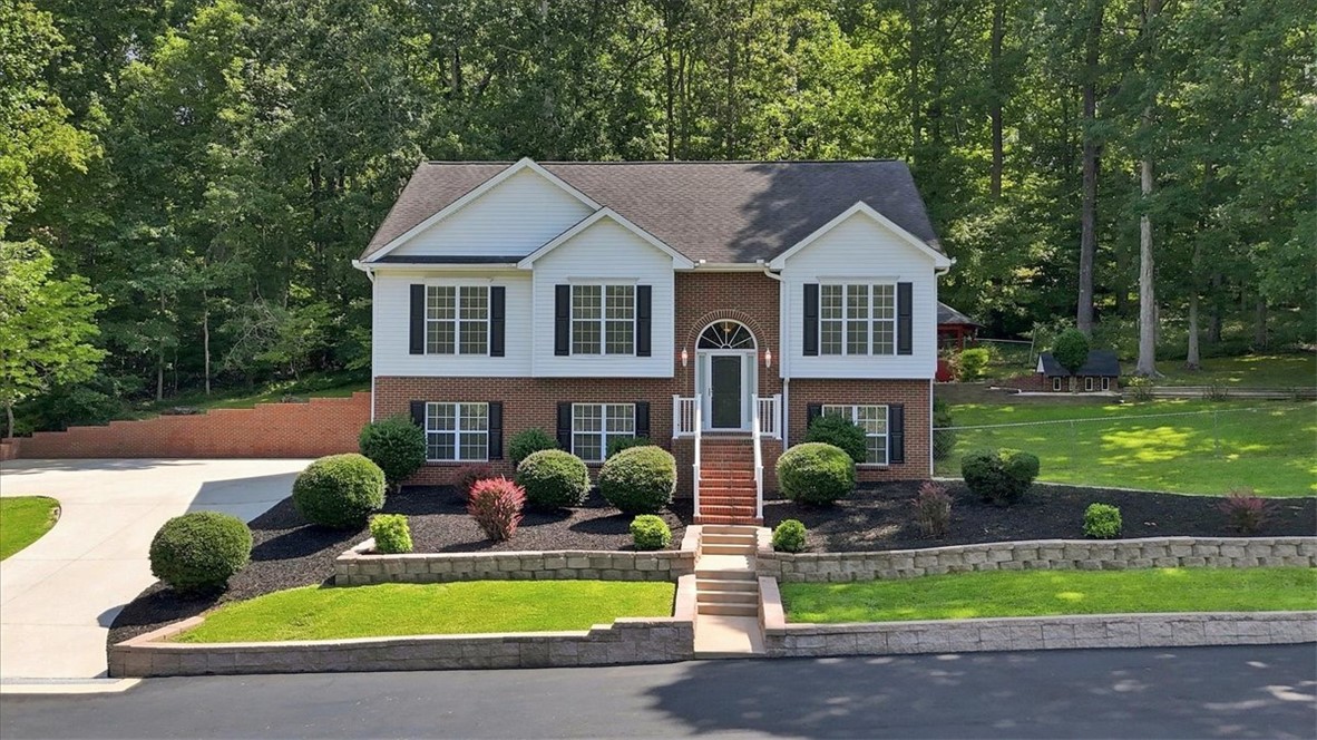 1052 Madden Bridge Road Central, SC 29630 - Photo 1 of 50 Mature trees frame a classic brick and siding exterior featuring manicured multi-level landscaping.
