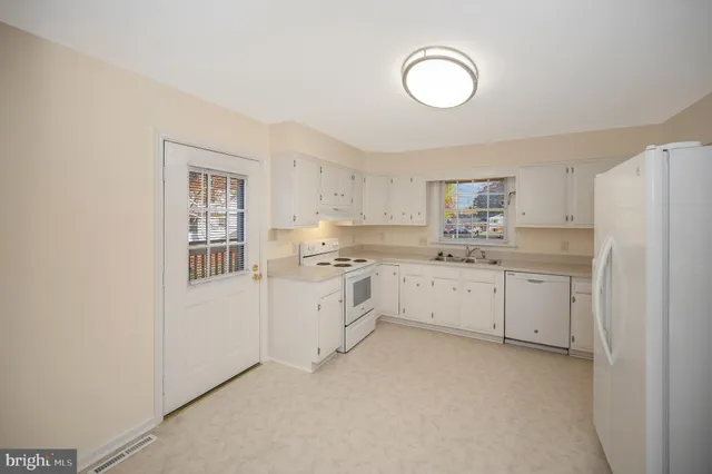 a kitchen with white cabinets and white appliances