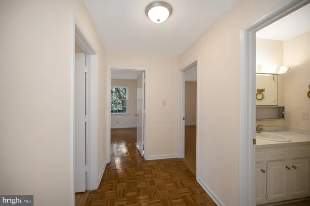 a view of a hallway with wooden floor and a bathroom