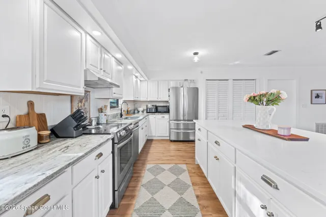 a large kitchen with stainless steel appliances lots of counter space and wooden floor