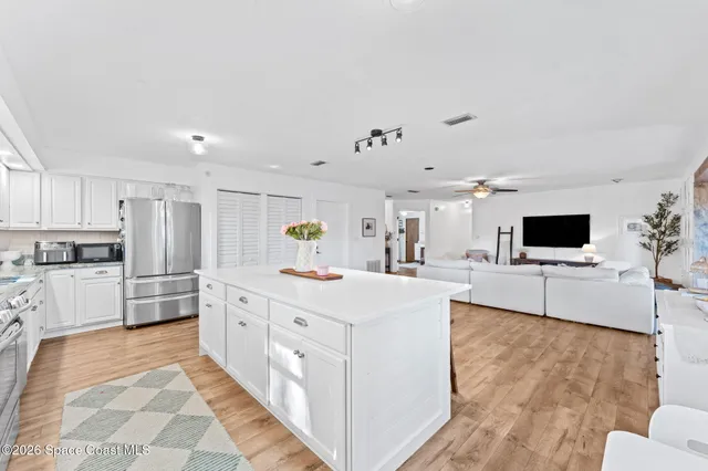 a large white kitchen with stainless steel appliances kitchen island granite countertop a refrigerator and a stove top oven